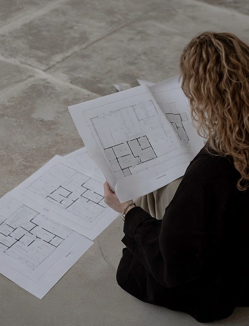 Interior designer reviewing architectural floor plans on a concrete floor