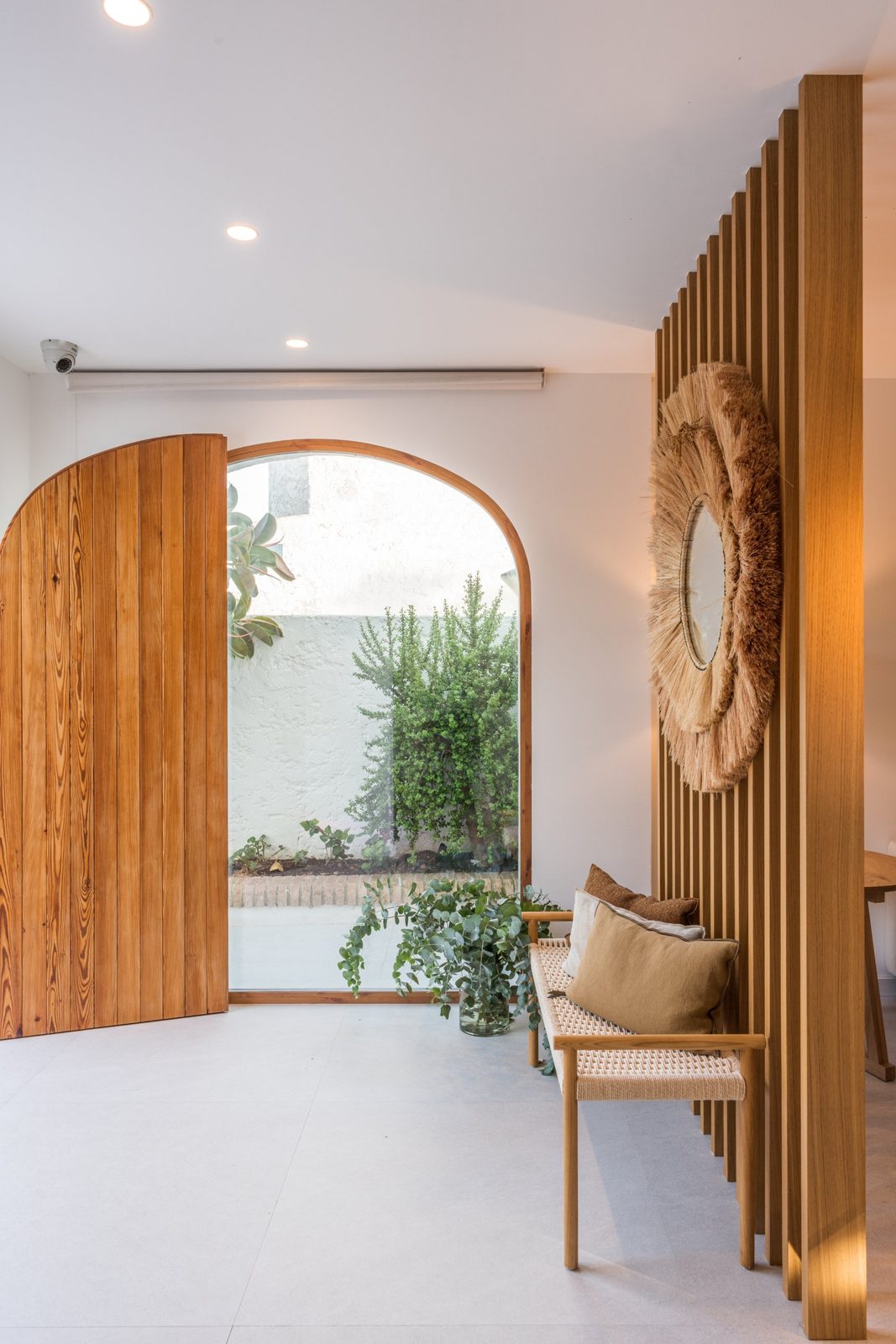Entrance with an arched timber door, arched window to the patio and an oak slatted screen