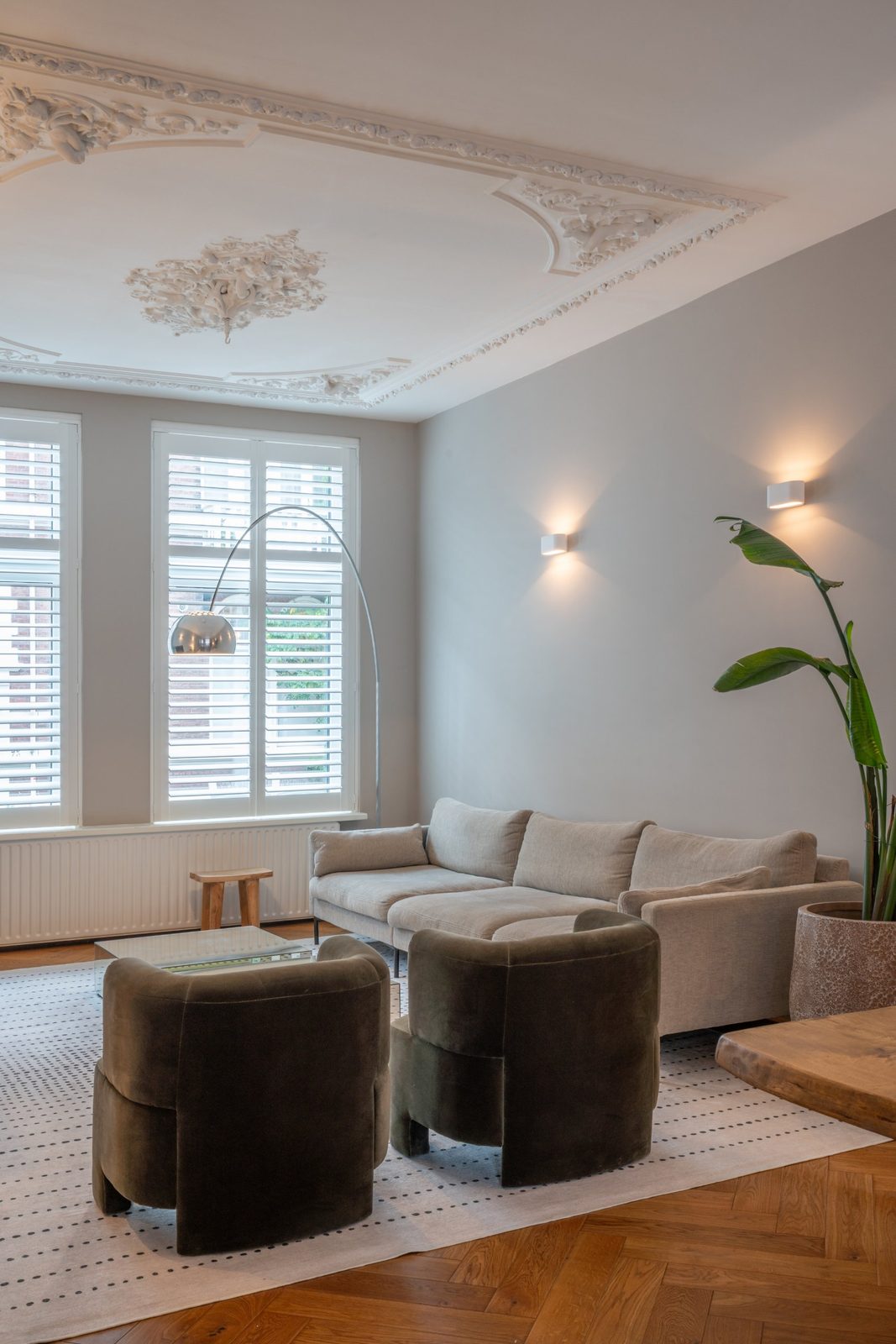 Living room with ornate plaster ceiling, plantation shutters, arc floor lamp and olive velvet armchairs