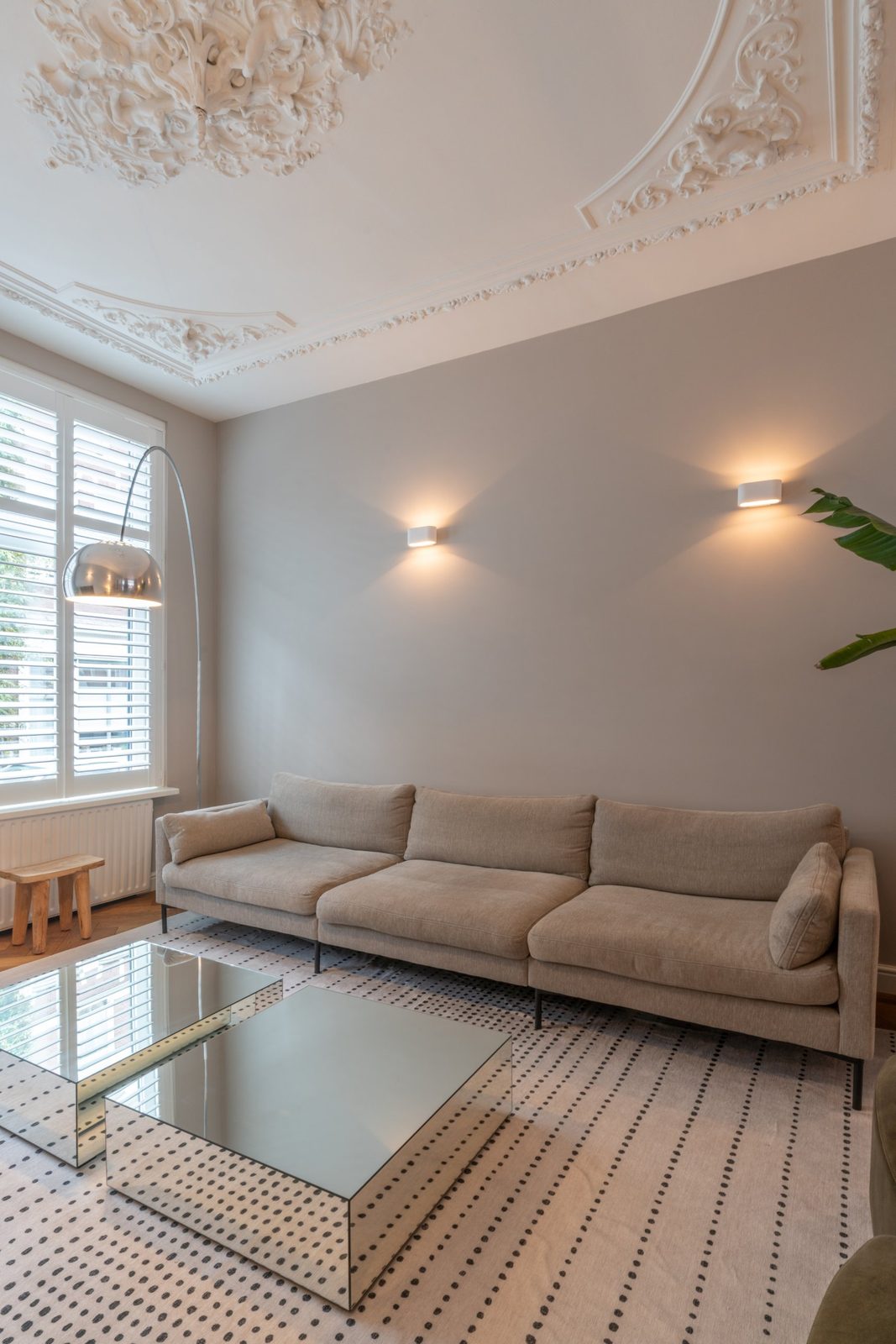 Three-seat linen sofa against a warm grey wall lit by two plaster wall lights