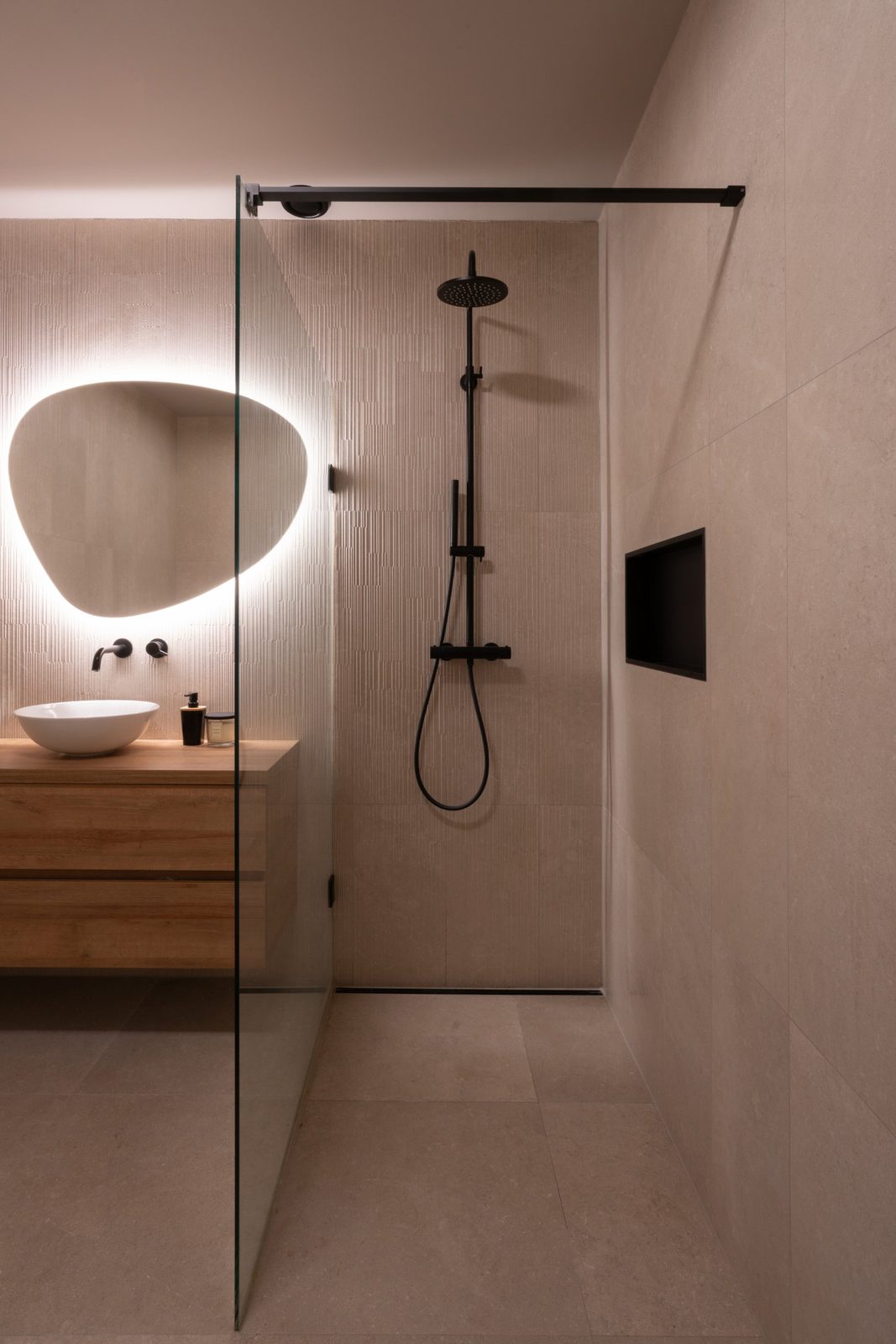 Walk-in shower with black rain shower, recessed niche and warm stone-look tiles
