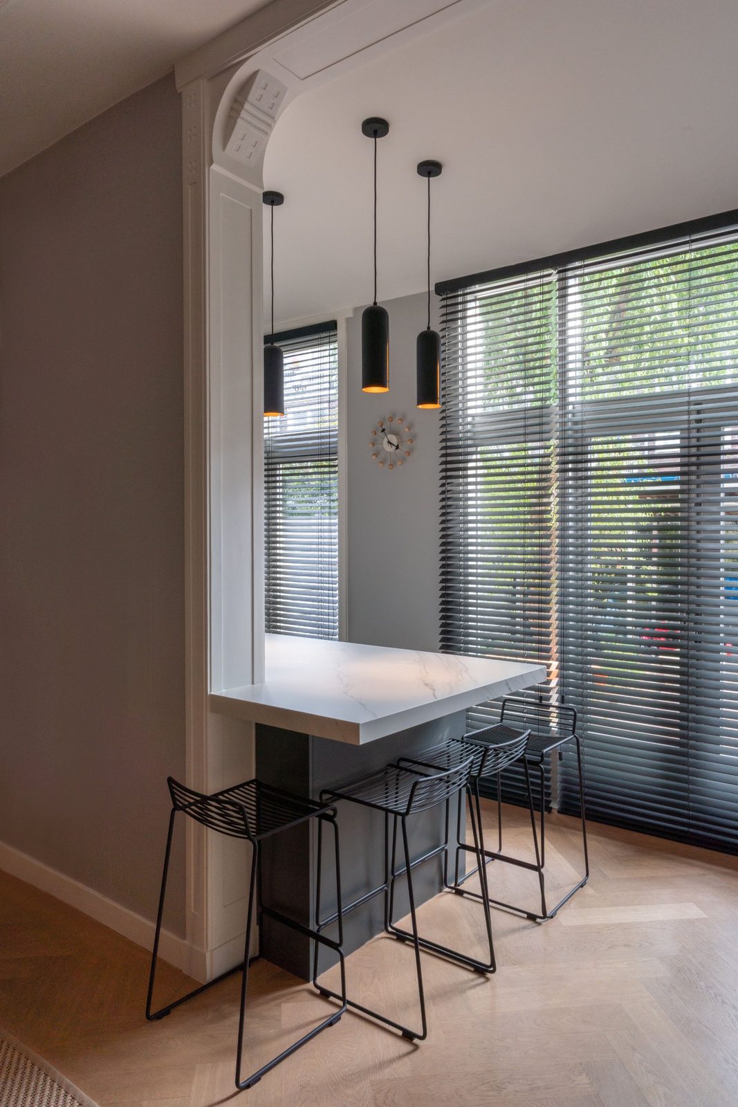 Breakfast bar with wire stools and black pendants under an original moulded arch