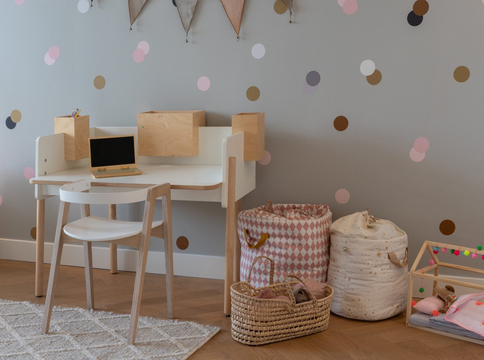 Children's room with a small desk, woven baskets and a polka-dot wall