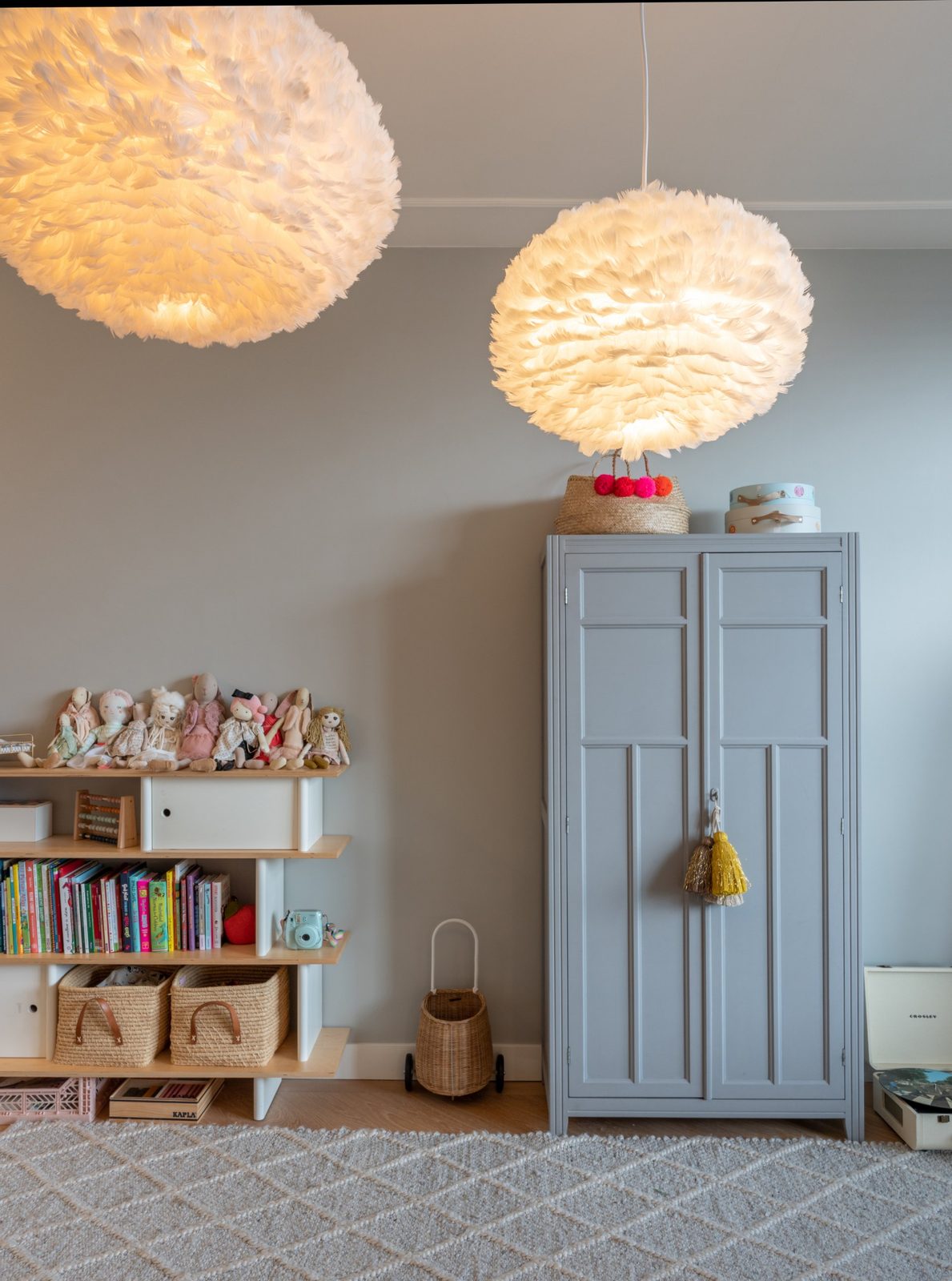 Children's room with feather pendant lights, painted wardrobe and low bookshelf