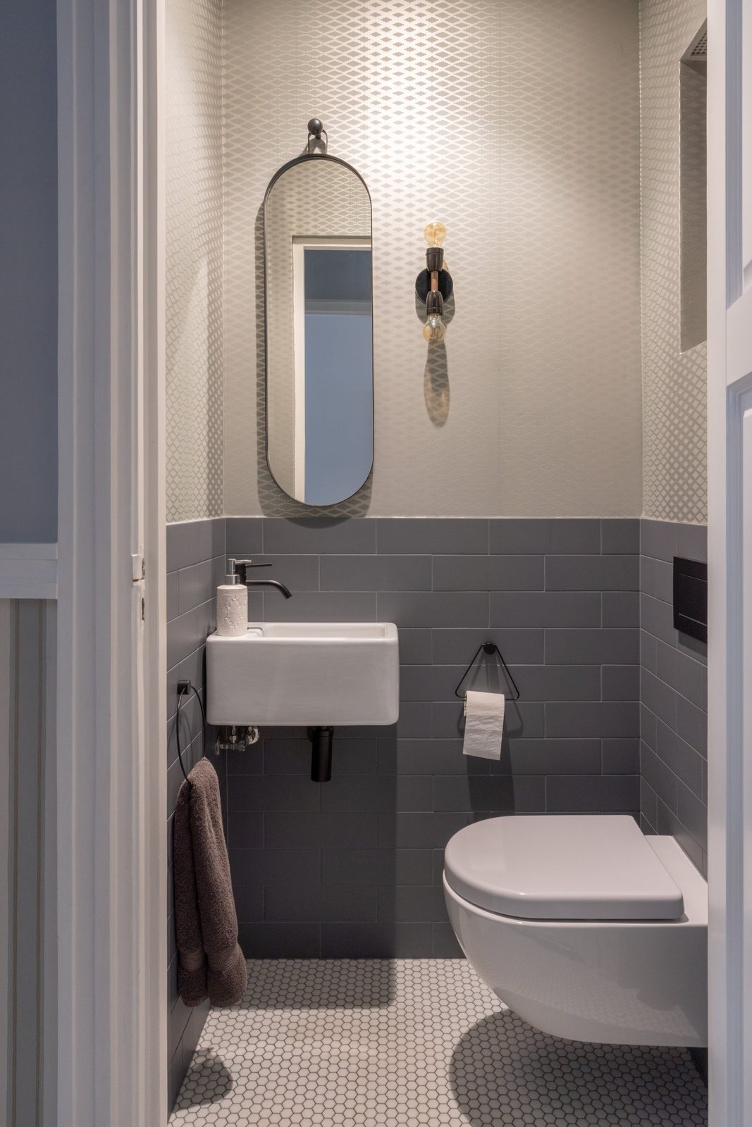 Guest toilet with geometric wallpaper, grey brick tiles and a small white basin