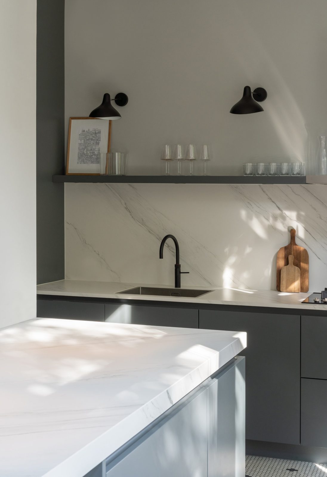 Kitchen with marble-look splashback, dark grey cabinets, open shelf and black wall lights
