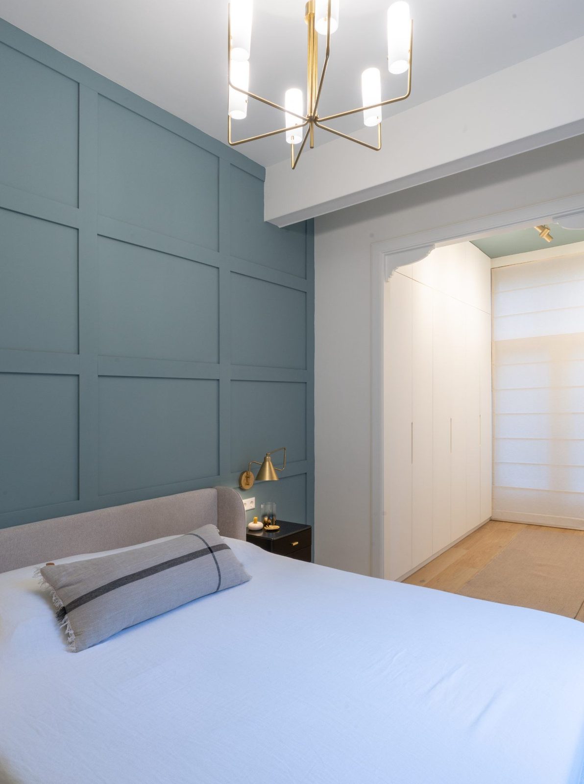 Blue-panelled bedroom with a brass lamp and bespoke wardrobe