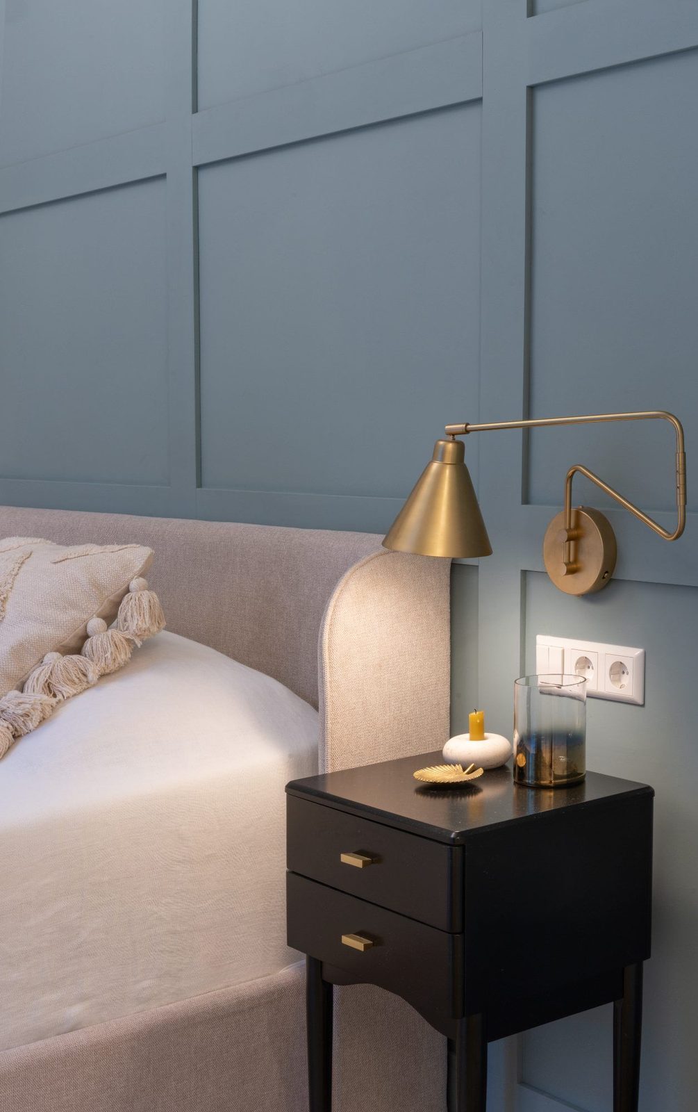 Bedroom with blue panelling and a brass wall light