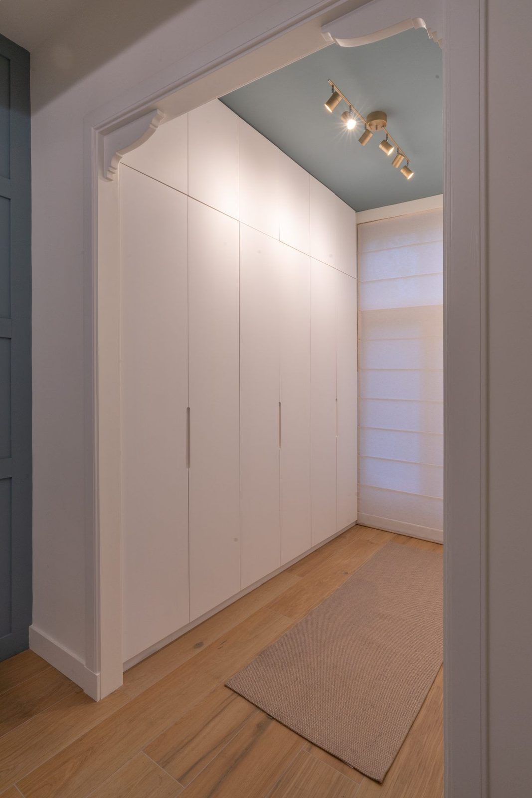 Walk-in wardrobe with bespoke cabinetry beneath the original cornice