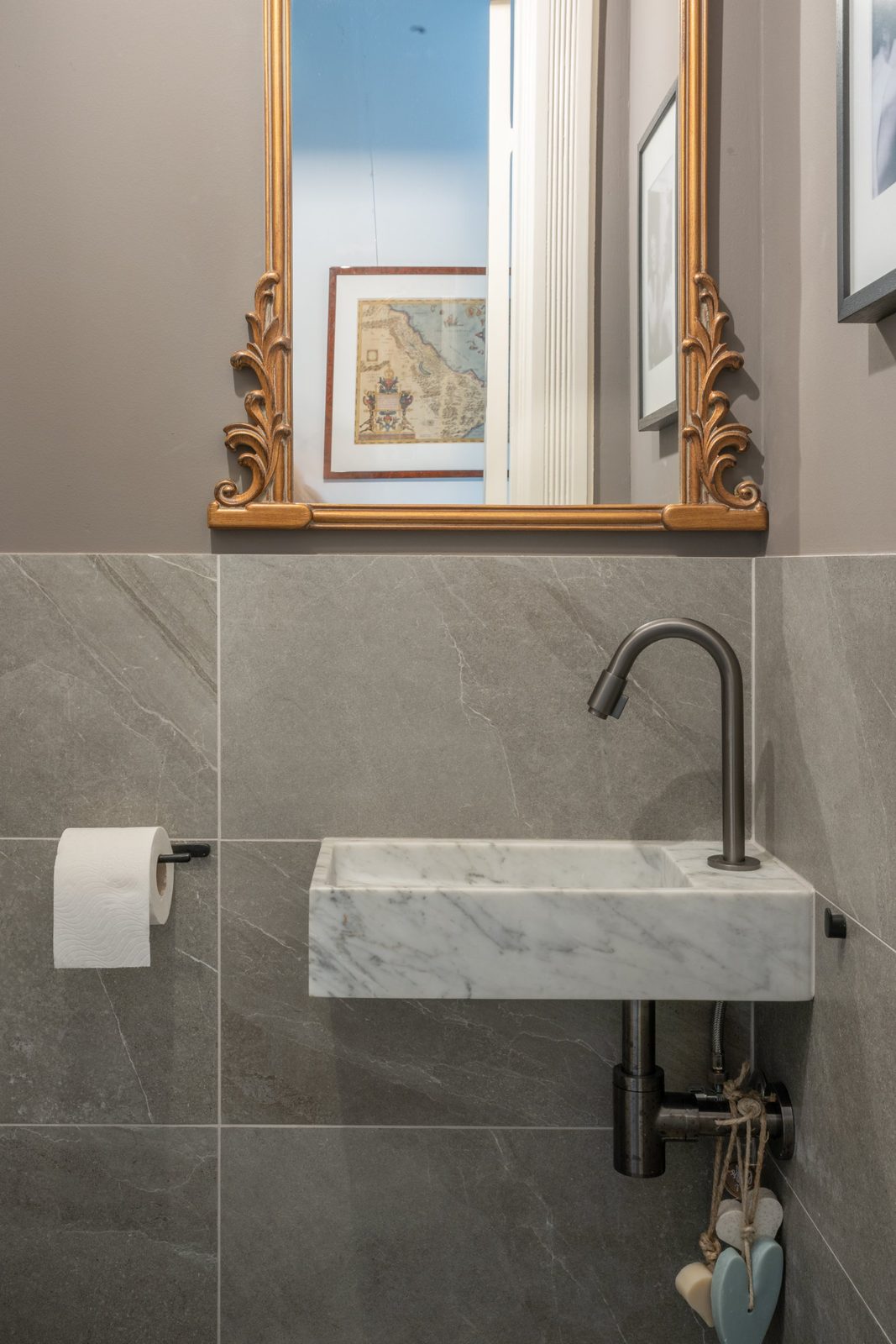 Guest toilet with a marble basin, gunmetal tap and gilded antique mirror